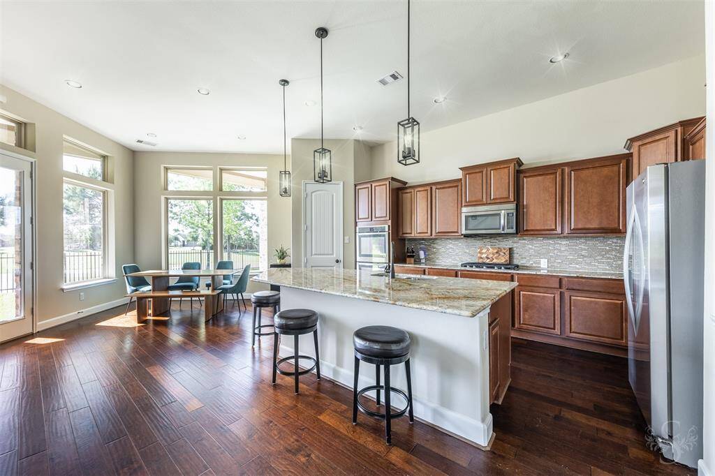 This gourmet kitchen features DOUBLE ovens, gas cooktop, stainless appliances, large island with seating for up to 5, granite counters and tile backsplash and recent pendant lights.