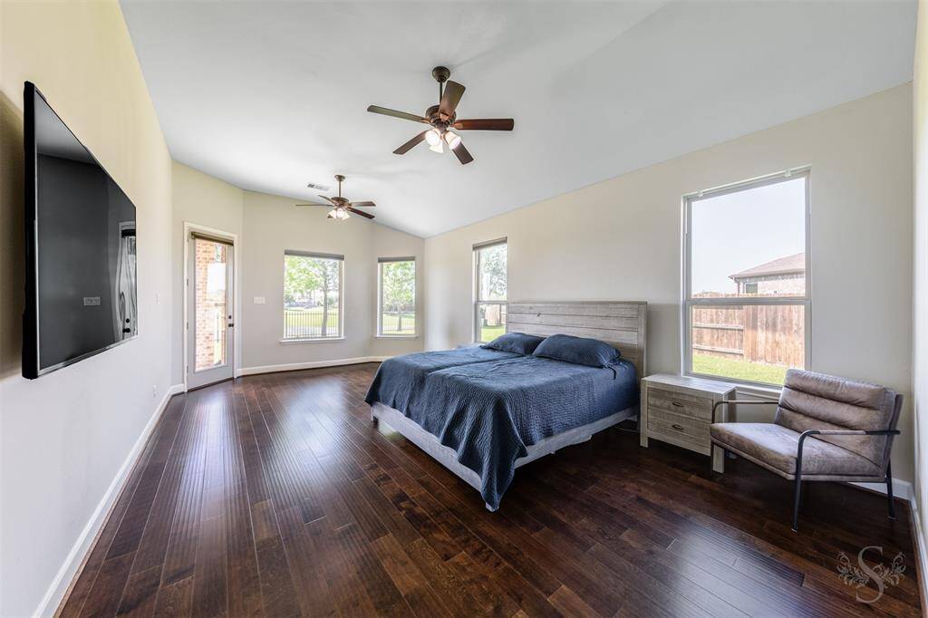 Big beautiful Primary bedroom with hardwood floors and sloped ceiling and two fans! Views right out to the lake.
