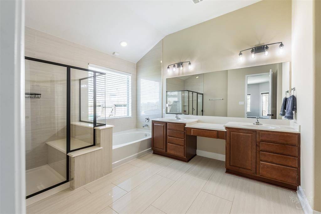 Sparkling Primary bathroom with tile floors and walls, double sinks and soaking tub with big walk in shower.