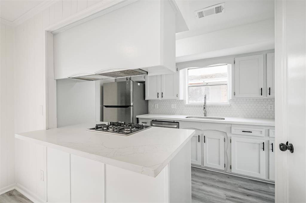 The kitchen features new quartz countertops and a gas cooktop, complemented by a breakfast bar.