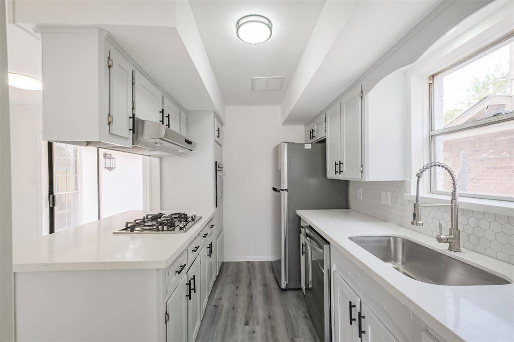 Newly installed stainless steel appliances and an undermount sink, complemented by a stylish tile backsplash.