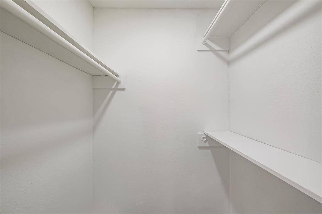 The primary bedroom features a closed storage area with shelves and wooden doles for hanging clothing.