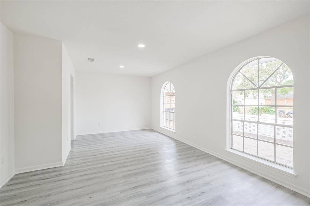 The formal living and dining room features recessed lighting and a spacious, rounded window.