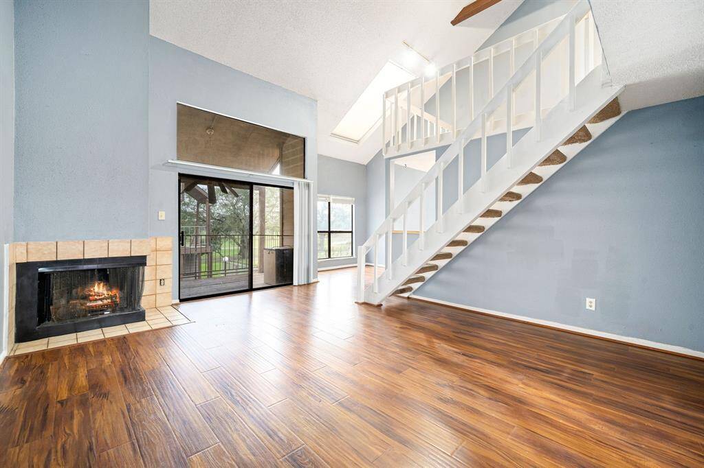 This bright living room features a cozy fireplace and wood flooring.