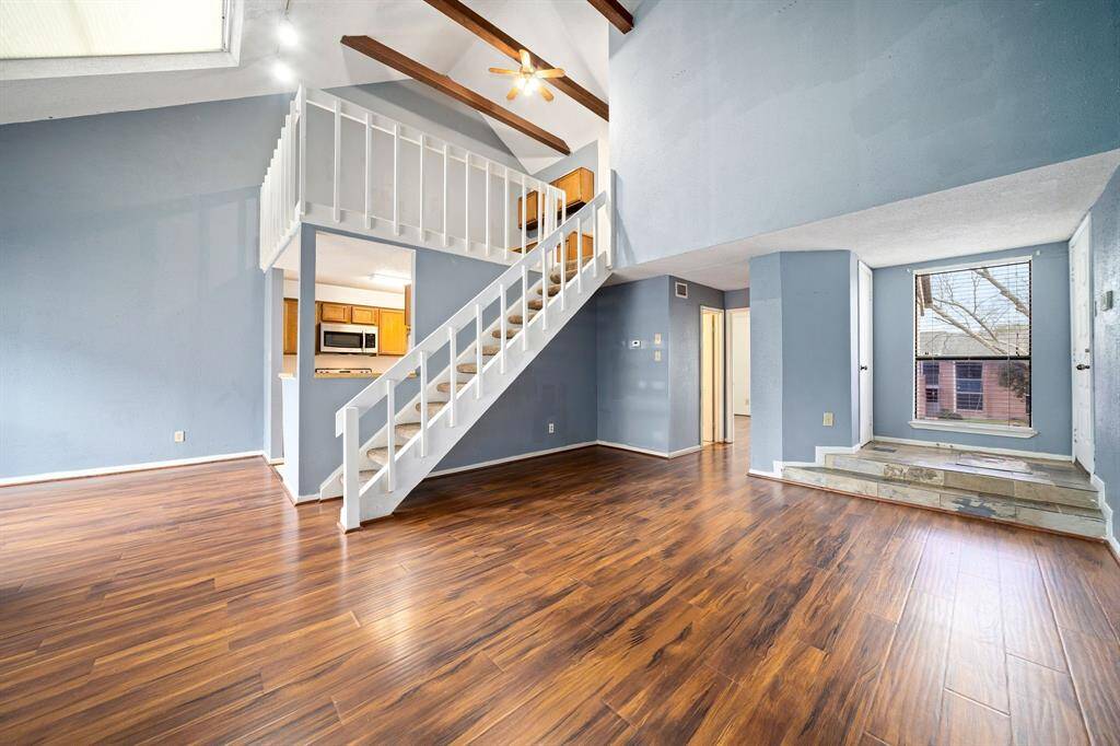 A white staircase adds elegance, connecting to a loft space.