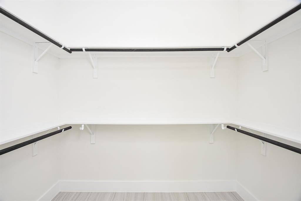 This exquisite ensuite offers a spa-like retreat, featuring dual sinks on a gleaming quartz countertop and an oversized glass shower. Elegant gold accents and sleek finishes complete this sophisticated primary bath.