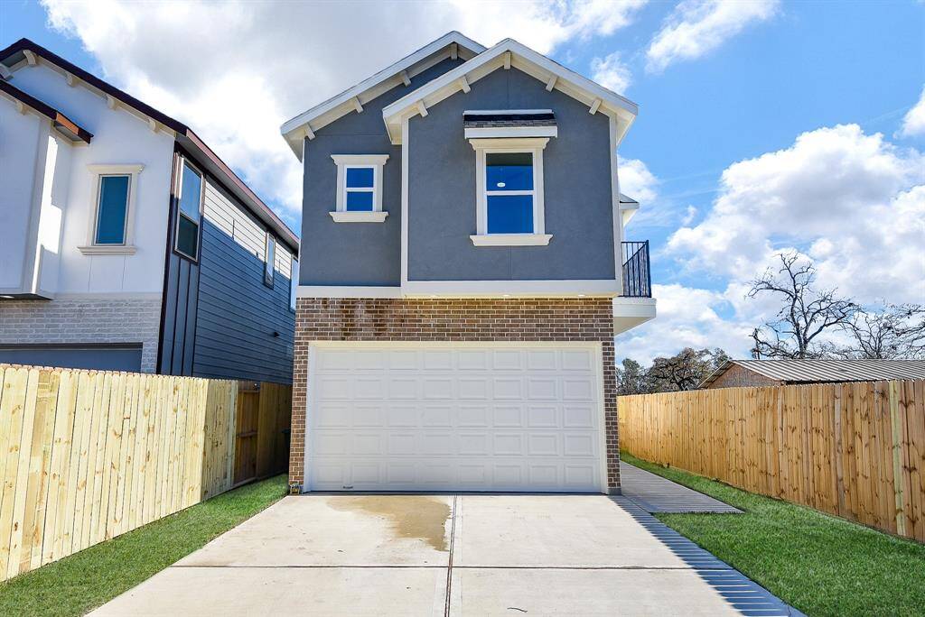 The driveway leads to a two-car attached garage with a sleek wrought iron gate, providing ample parking and added privacy.