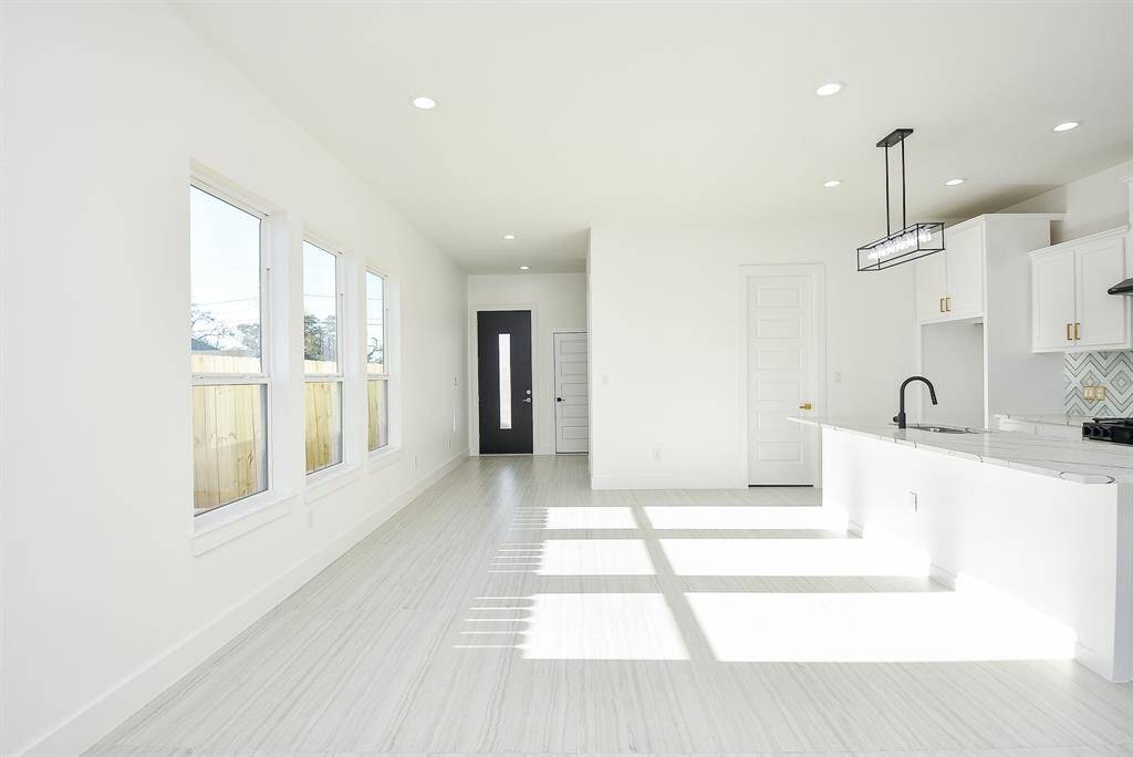 A chef’s dream! This well-lit open kitchen is perfect for entertaining, featuring a spacious quartz island with breakfast bar seating, sleek stainless steel appliances, and elegant gold hardware. The stunning backsplash adds a touch of luxury to this modern culinary space.
