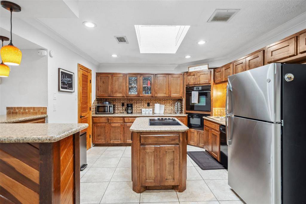 Kitchen is equipped with island cook-top, double ovens and many lovely solid wood cabinets.