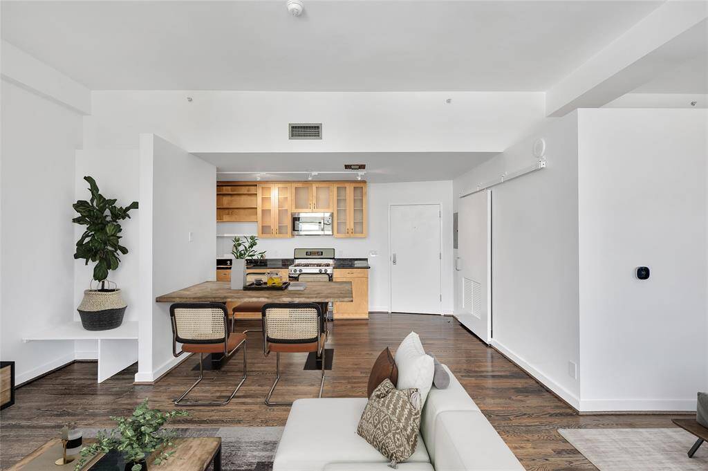 Solid oak hardwood floors stained a warm color is wonderful contrast to the clean crisp white interior paint. Entry door to unit to right of Kitchen. Laundry & Mechanical closet behind barn door on right. PHOTO VIRTUALLY STAGED.