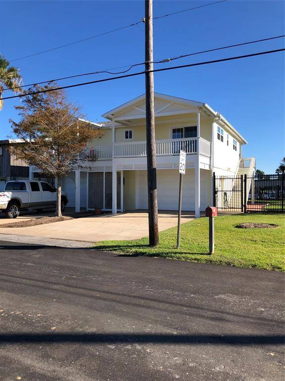 This two-story home features a spacious balcony and a double garage. It has a driveway, spacious front lawn, and is enclosed by a fence on a corner lot.