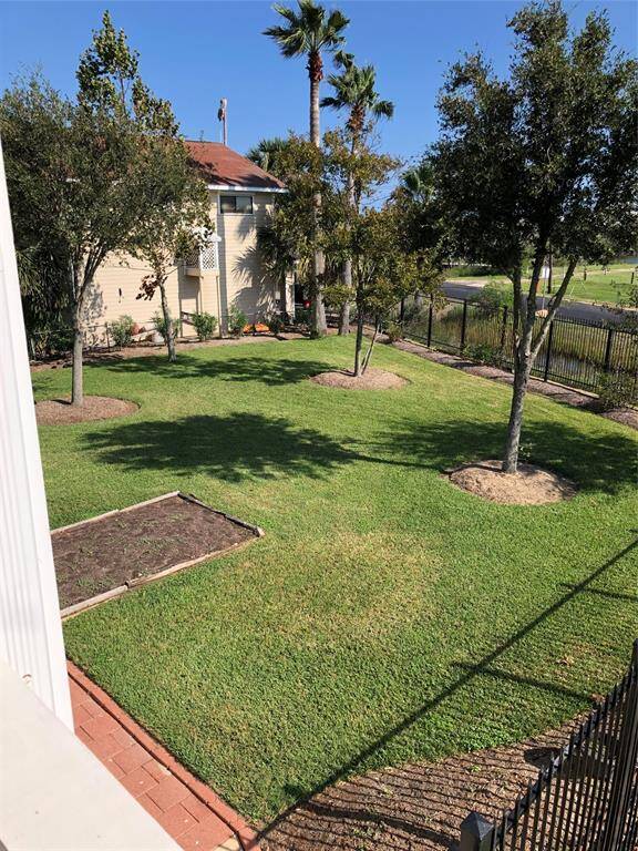 Spacious backyard with well-maintained lawn, mature trees, and a small garden bed. Features a metal fence, Ideal for outdoor activities.