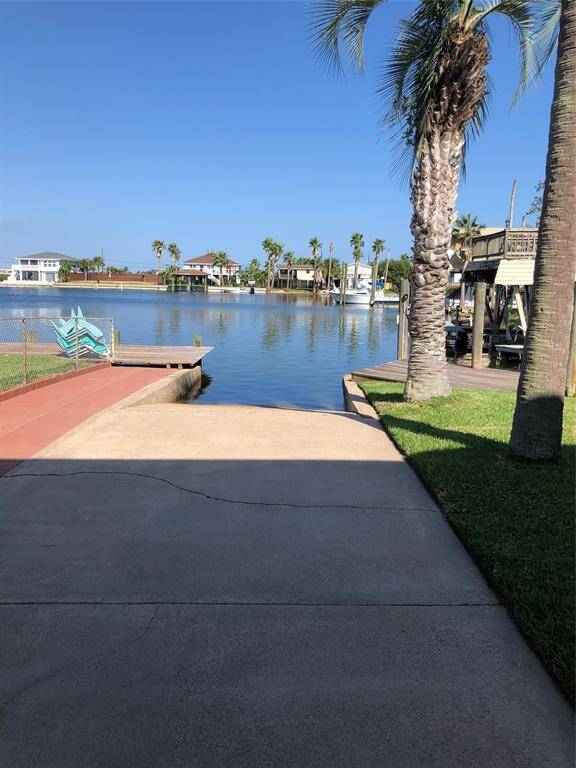 A serene waterfront property featuring a private boat launch, palm trees, and a clear view across a calm waterway, perfect for enjoying coastal living.