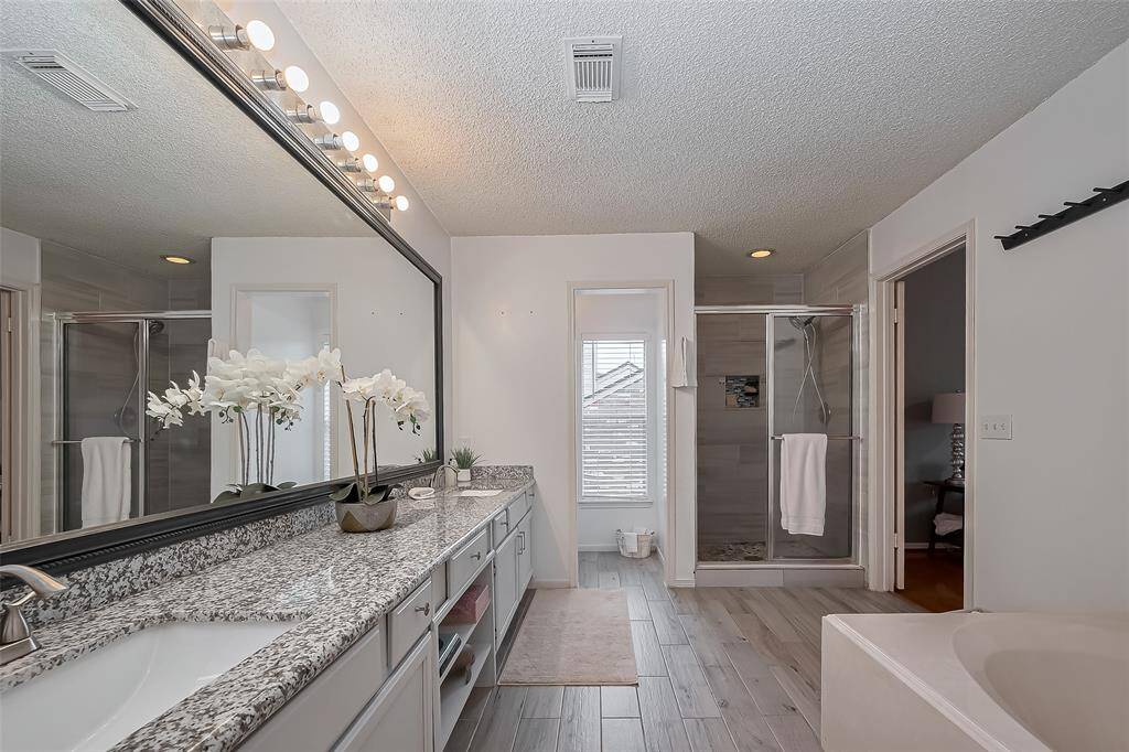 The primary bathroom offers a spacious granite countertop with an extended mirror, providing plenty of room for daily routines. Enjoy the comfort of a relaxing garden tub and the convenience of a separate walk-in shower, creating a perfect blend of luxury and functionality.