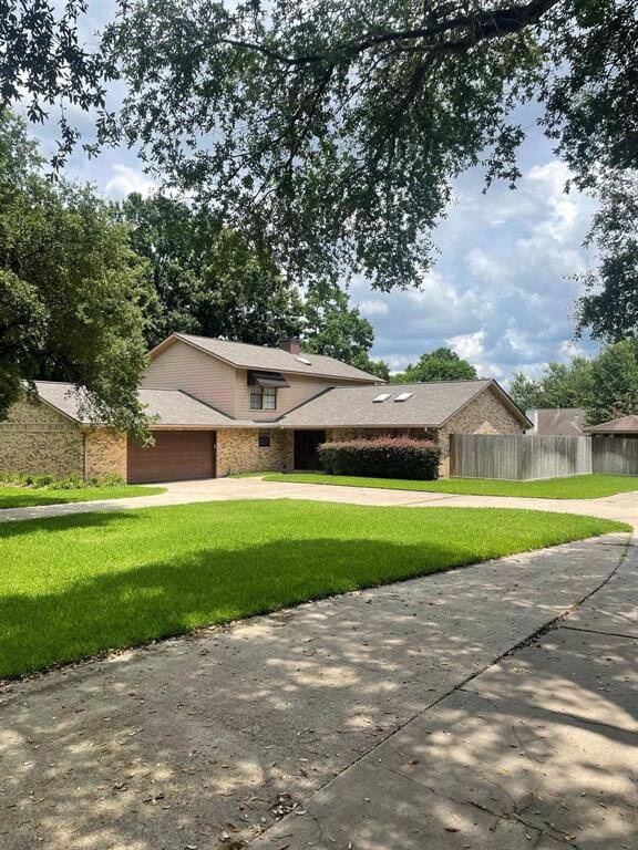 This photo shows a spacious two-story brick home with a well-maintained lawn and mature trees. It features a large driveway leading to a two-car garage, providing ample parking space. The house is set in a peaceful neighborhood.