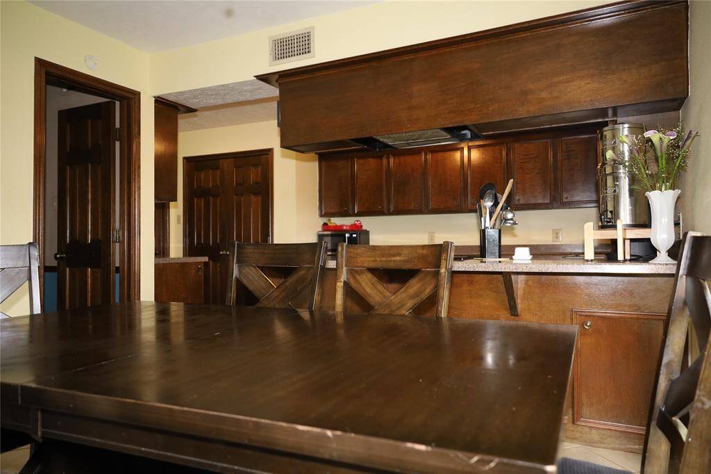 Elegant dining room featuring a large wooden table with matching chairs, a classic chandelier, and ample natural light from two windows.