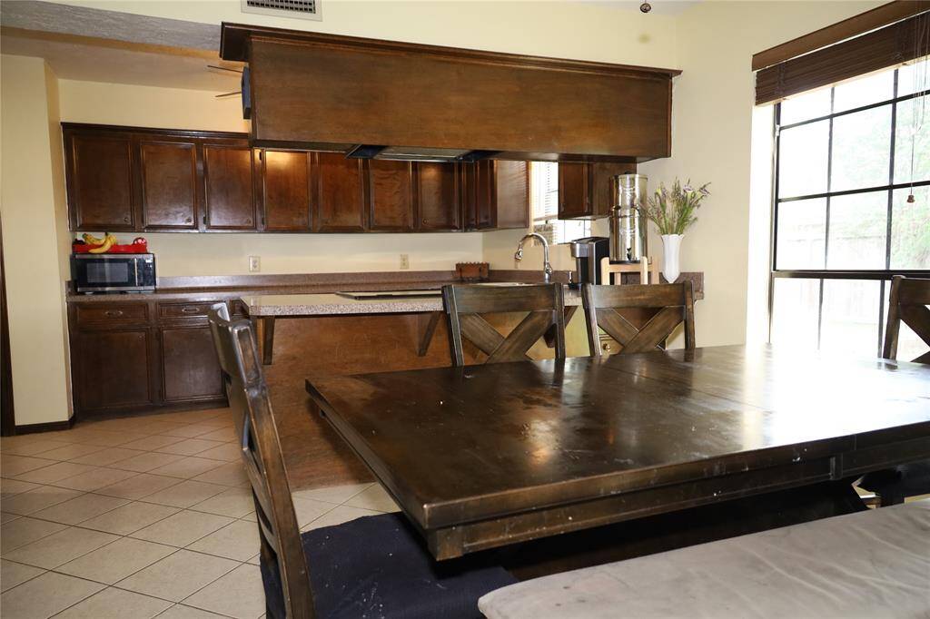 This photo shows a spacious two-story brick home with a well-maintained lawn and mature trees. It features a large driveway leading to a two-car garage, providing ample parking space. The house is set in a peaceful neighborhood.