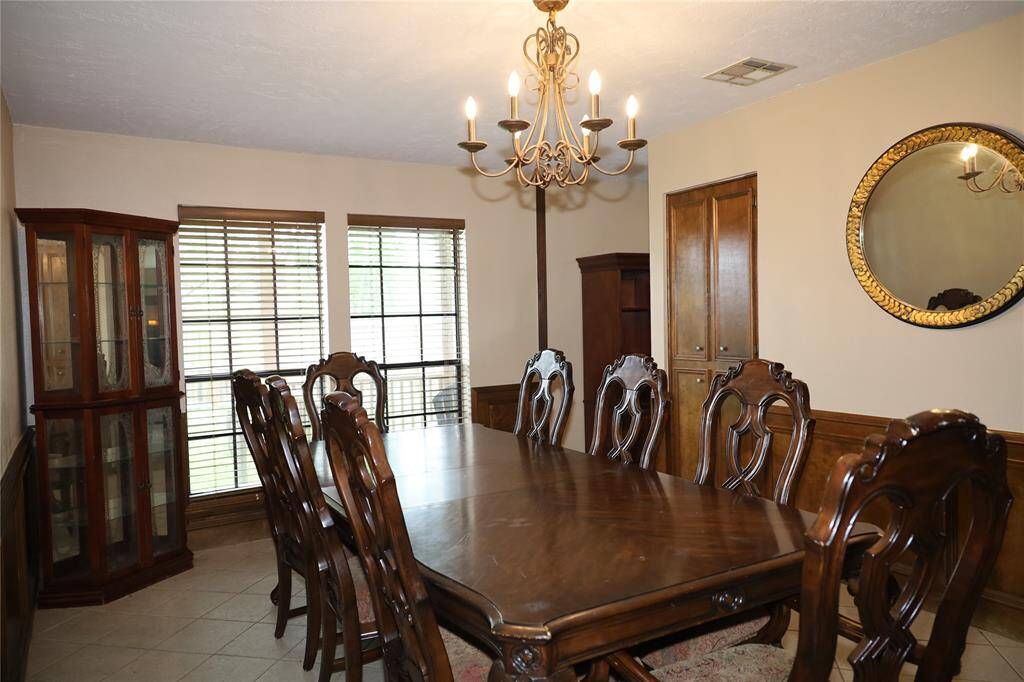 Spacious living room with carpeted flooring, featuring cozy sofas and a central coffee table. It includes a ceiling fan, a prominent fireplace, and an entrance with decorative glass doors, creating a warm and inviting atmosphere.