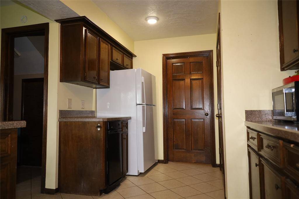This photo shows a spacious two-story brick home with a well-maintained lawn and mature trees. It features a large driveway leading to a two-car garage, providing ample parking space. The house is set in a peaceful neighborhood.