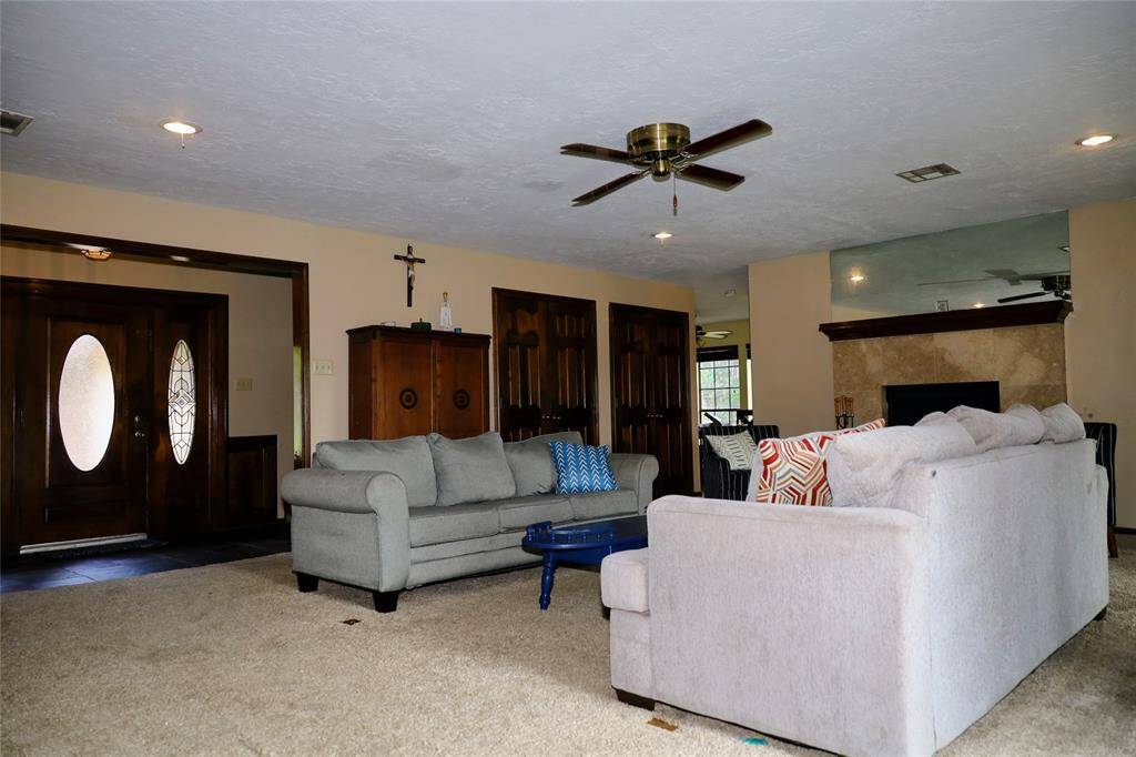 This photo shows a spacious two-story brick home with a well-maintained lawn and mature trees. It features a large driveway leading to a two-car garage, providing ample parking space. The house is set in a peaceful neighborhood.