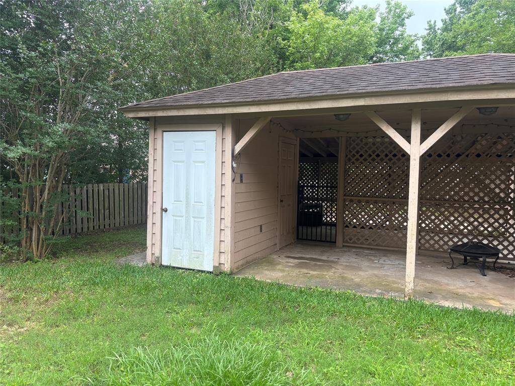 This photo showcases a two-story brick home with a spacious backyard, wooden deck, and upper-level balcony. The area is enclosed by a wooden fence and surrounded by mature trees, offering a private and inviting outdoor space.
