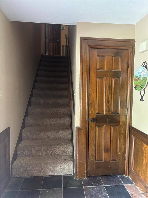 This photo shows a spacious two-story brick home with a well-maintained lawn and mature trees. It features a large driveway leading to a two-car garage, providing ample parking space. The house is set in a peaceful neighborhood.