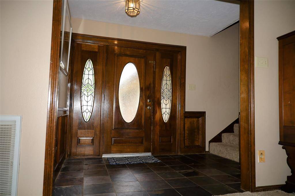 This photo shows a spacious two-story brick home with a well-maintained lawn and mature trees. It features a large driveway leading to a two-car garage, providing ample parking space. The house is set in a peaceful neighborhood.