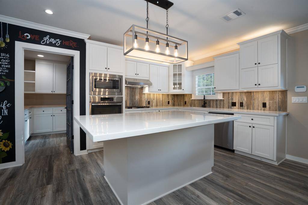 A chef's kitchen with a huge pantry, stainless appliances and quartz counters.