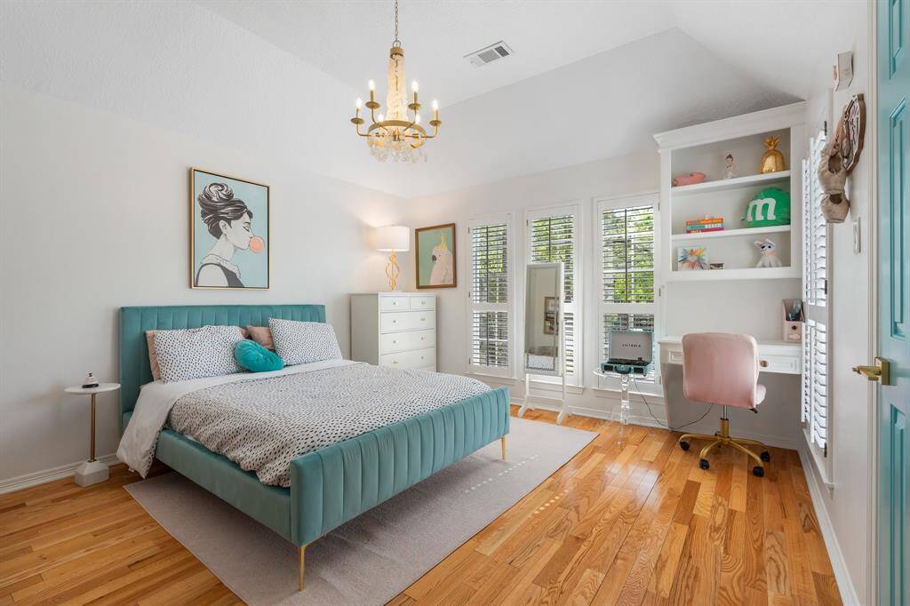 This beautiful bedroom boasts rich wood flooring, a soaring high ceiling, and an abundance of natural light, creating a warm and inviting retreat.
