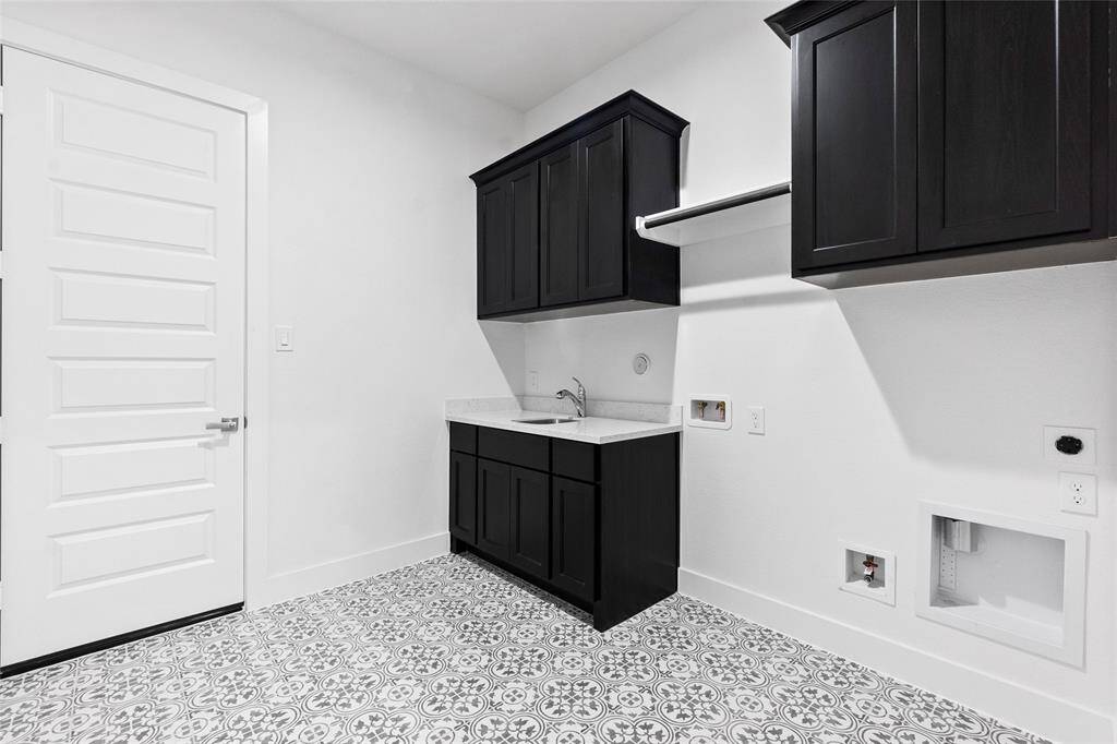 Spacious Utility Room with Sink, Washer and Dryer Connections, Drying Bar, and Storage Cabinets.