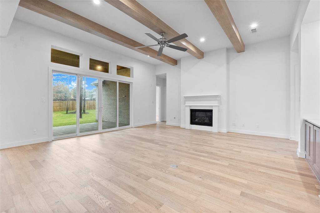 Wood Beams, Gas Fireplace, and Sliding Glass Doors to the Covered Patio Highlight the Family Room
