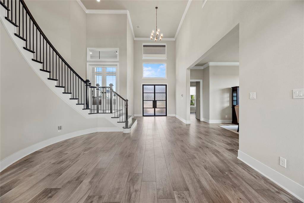 A striking double iron front door opens to a grand entryway, featuring dual light fixtures and elevated access to the study just a few steps up
