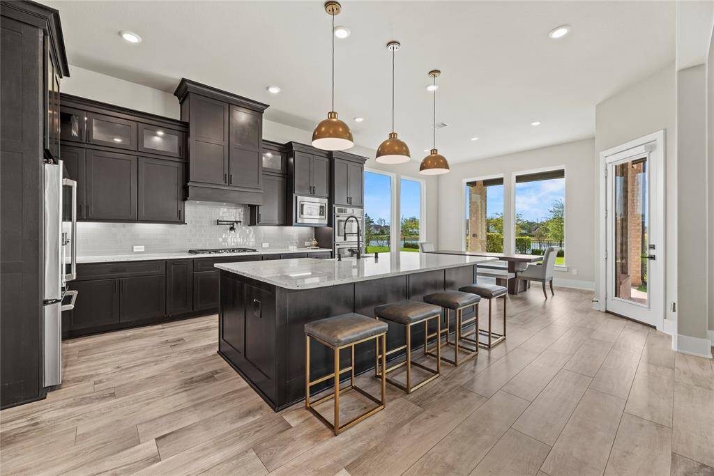 The kitchen features stainless steel appliances, including a wine fridge, double ovens, a 5-burner gas stove, and a convenient pot filler—perfect for both everyday cooking and entertaining.