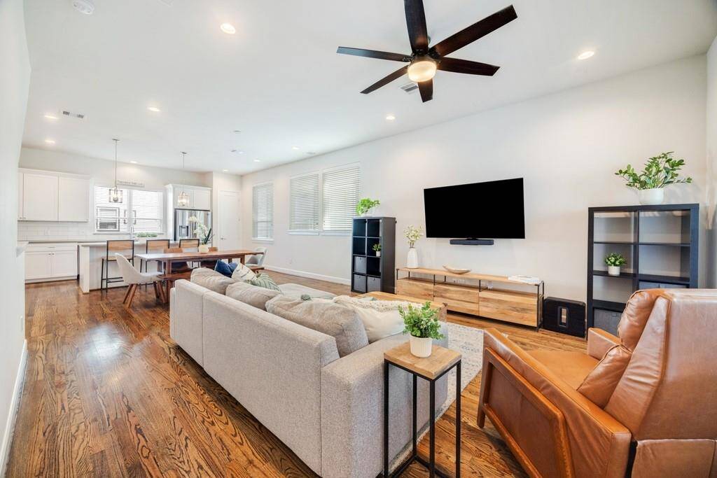 Additional view of the open floor plan highlights the gorgeous hardwood floors, abundant natural light, and window coverings throughout the home.