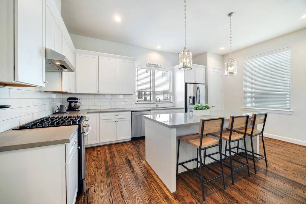 Upstairs on the second floor, the open floor plan showcases beautiful hardwood floors, a stylish kitchen, abundant natural light, and access to a private balcony.