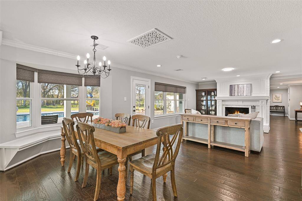 Just beyond the living room space and open to the kitchen, you'll find this casual dining space that showcases a stylishly updated candelabra chandelier, wood floors neutral paint trimmed with crown molding, and a bay window seat overlooking the pool and acreage beyond.