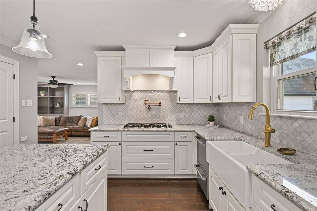 The chef of the house will LOVE the amenities that include an apron front dual basin sink with a brushed gold gooseneck faucet, a 5-burner propane gas cooktop with a pot filler, a built-in refrigerator with cabinet fronts, a single oven, and a double drawer dishwasher.