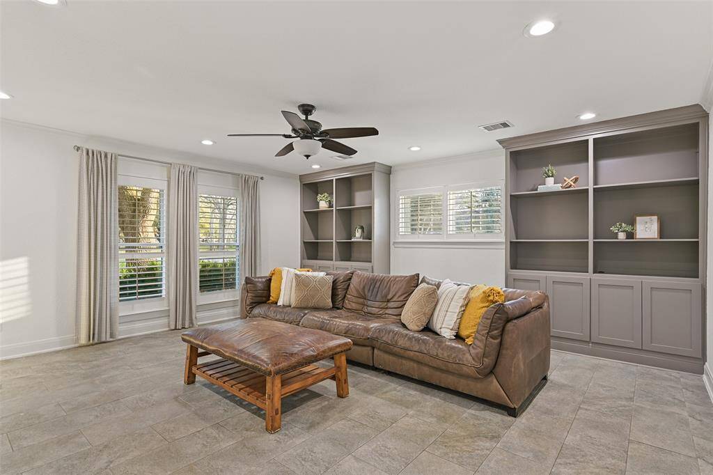 Beyond the kitchen, at the far end of the home, you'll find another living space. This one is more private and casual than the first - making it a great option for flopping out for a family movie night! Note the custom built-ins, recessed lights, tile floors, and windows with plantation shutters.