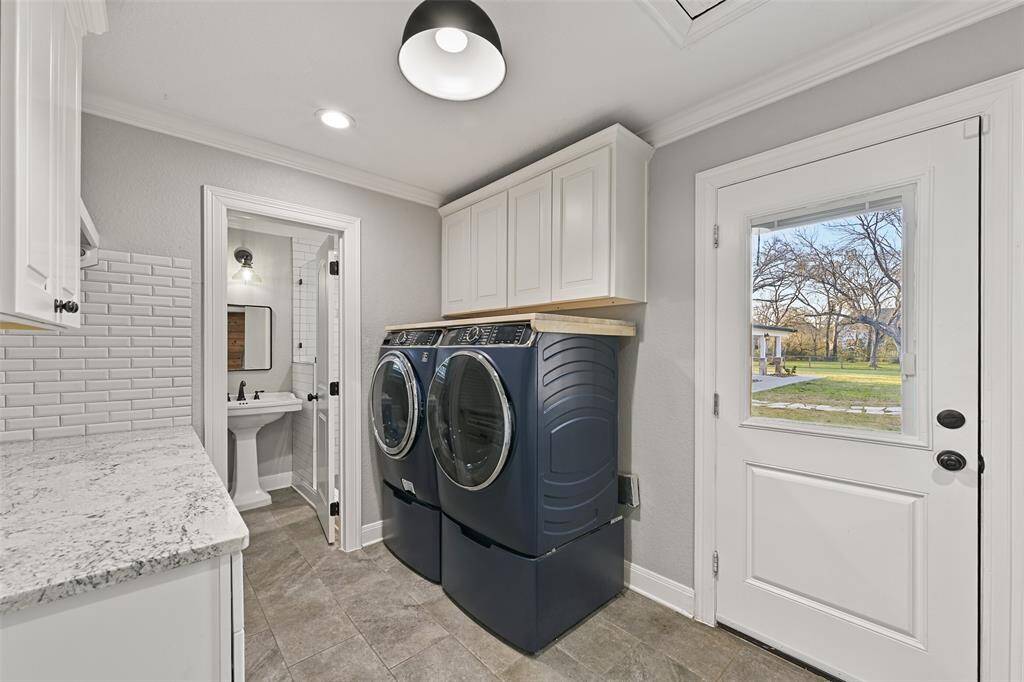 Just off of the den/gameroom in the previous photo, find this roomy utility room complete with a granite top folding counter, white cabinetry, a subway tile backsplash, tile floors, and a full bathroom that is accessible from the pool area via this exterior access door.
