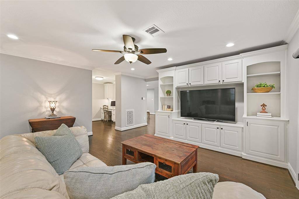 On the opposite side of the first floor, you'll find an entire owner's retreat, complete with its own private living space. Here, there is a wall-to-wall built-in entertainment center, recessed lights, a lighted fan, engineered wood floors, and an alcove with a built-in workstation.