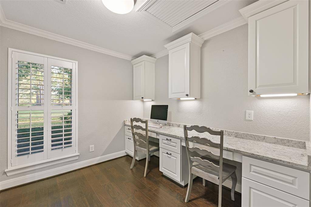 In this alcove off of the owners' suite, find a dual-station built-in desk that's perfect for a home management center or for working from home while enjoying the front yard views from the window dressed with plantation shutters.