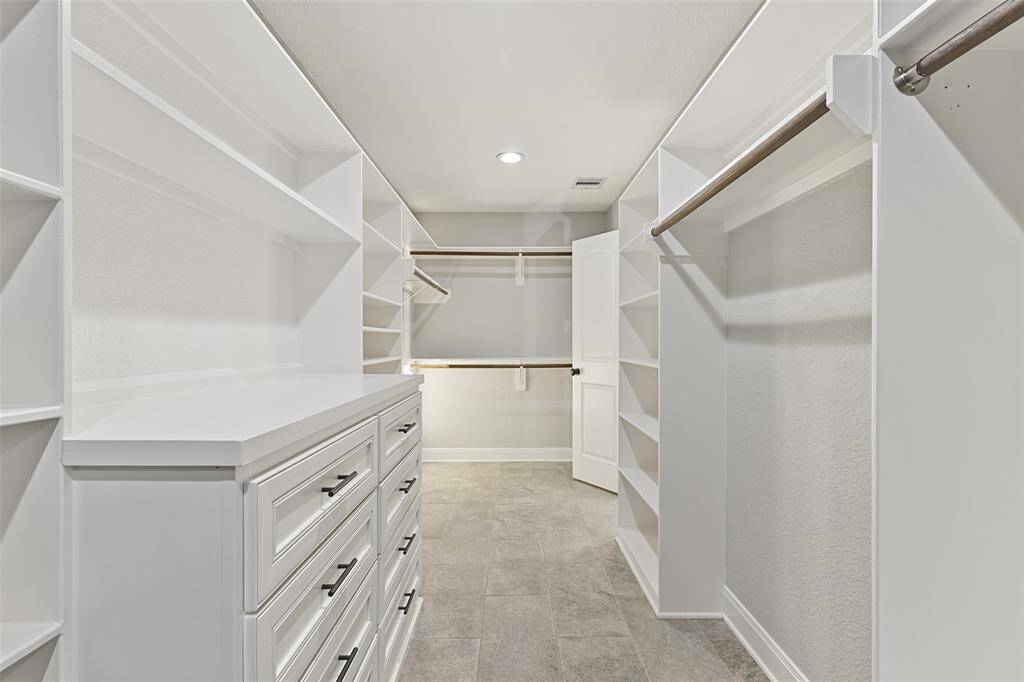Even the closet is noteworthy! There are entrances on either end with custom built-in drawers, shelving, and hanging rods that extend the entire length of the closet.