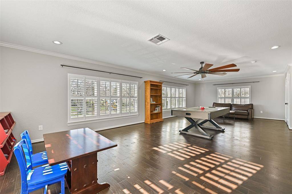 Head upstairs to find an impressively sized upstairs gameroom that measures 33'x18' and features an oversized ceiling fan, recessed lights, engineered wood floors, dual closets with built-in shelving, and sunlit windows shaded by plantation shutters.