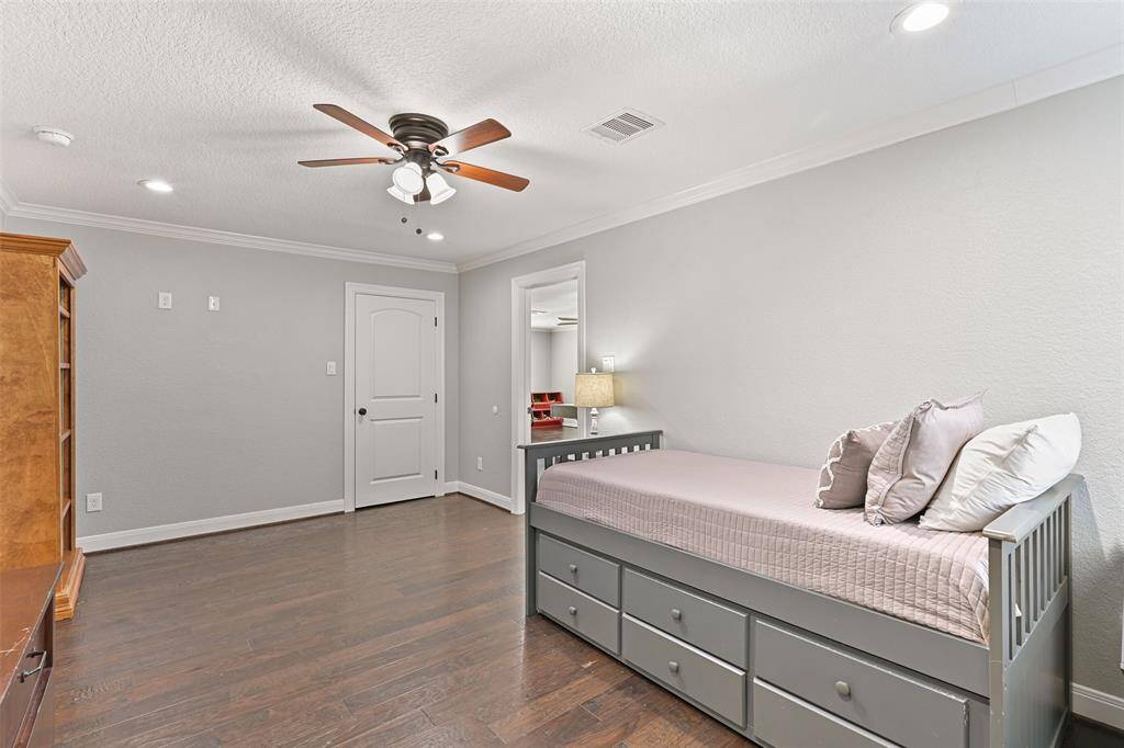 Another secondary bedroom is also located off of the game room and it also features a lighted ceiling fan, recessed lights, neutral paint, crown molding, engineered wood floors, and a window with plantation shutters.