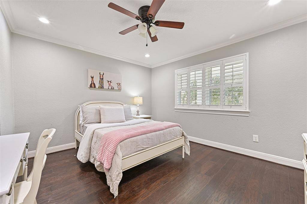 The remaining two secondary bedrooms are located on the front side of the second floor. Similar to the other bedrooms, these also feature a lighted ceiling fan, recessed lights, wood floors, neutral paint, crown molding, and windows with plantation shutters.