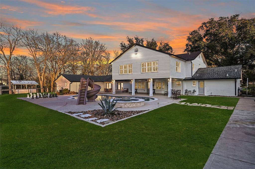An overview of the back of the home highlights the ample covered patio, pristine pool & spa with slide, backyard games, impressive chicken coop, bonus patio with outdoor kitchen & sauna, and the barn-style garage with tons of space & endless possibilities!