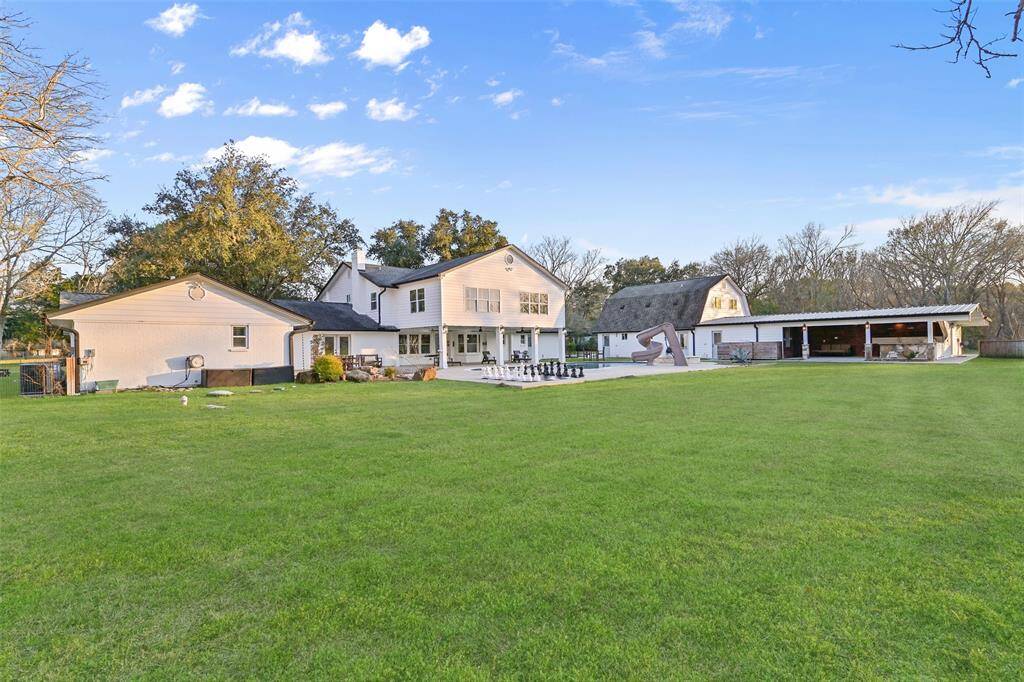 An overview of the back of the home highlights the ample covered patio, pristine pool & spa with slide, backyard games, impressive chicken coop, bonus patio with outdoor kitchen & sauna, and the barn-style garage with tons of space & endless possibilities!