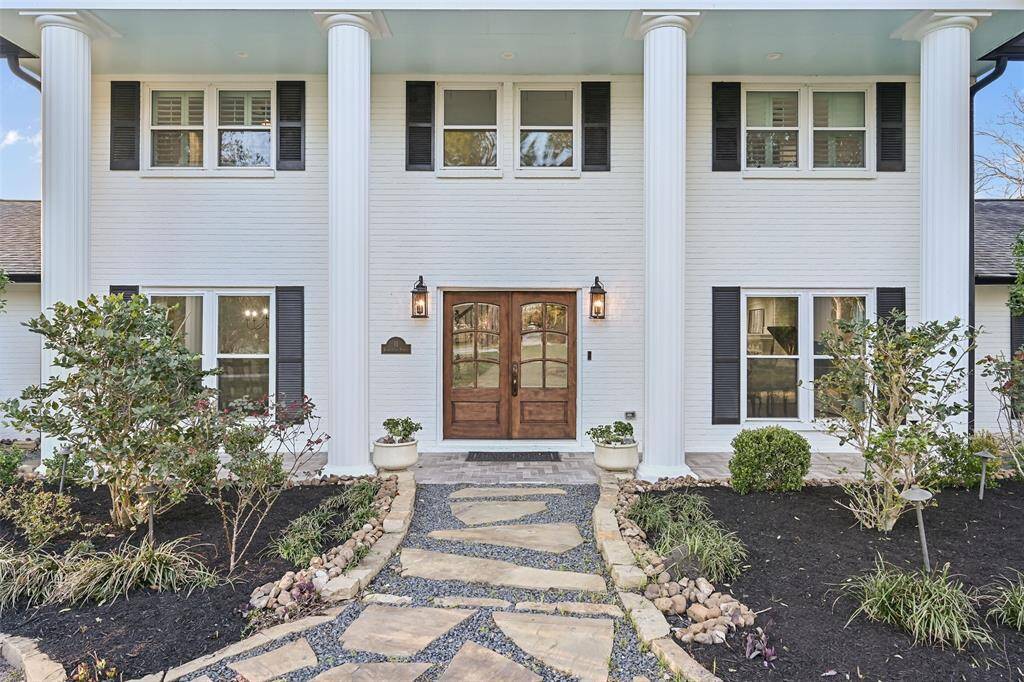 The home is truly grand - boasting a white-painted brick elevation accented by striking black shutters, elegant columns, old-world style carriage lamps,  numerous porches, sprawling trees, and the sounds of nature all around.
