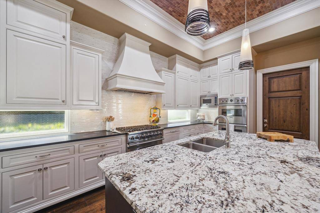 The custom hood is accentuated with a wall of neutral tasteful tile.  Natural light, of course!