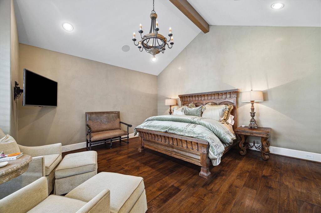 Generous first floor primary suite with wood beam vaulted ceiling creates a serene space for relaxation.